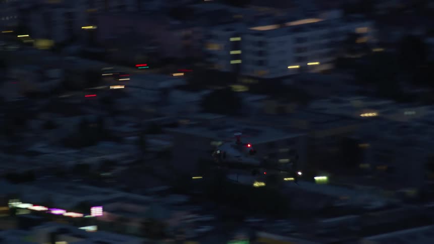 An LAPD helicopter flies over city buildings at twilight in Los Angeles California captured in beautiful aerial footage