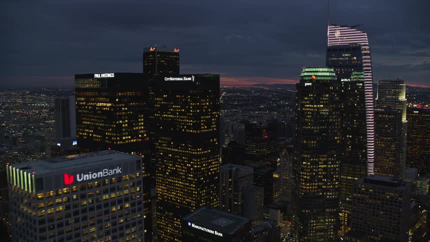 Flying through the towering skyscrapers of Downtown Los Angeles at sunset capturing the citys impressive superstructures and epic skyline