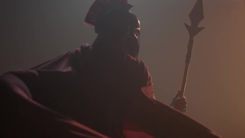 A man has a red cape and is holding a spear