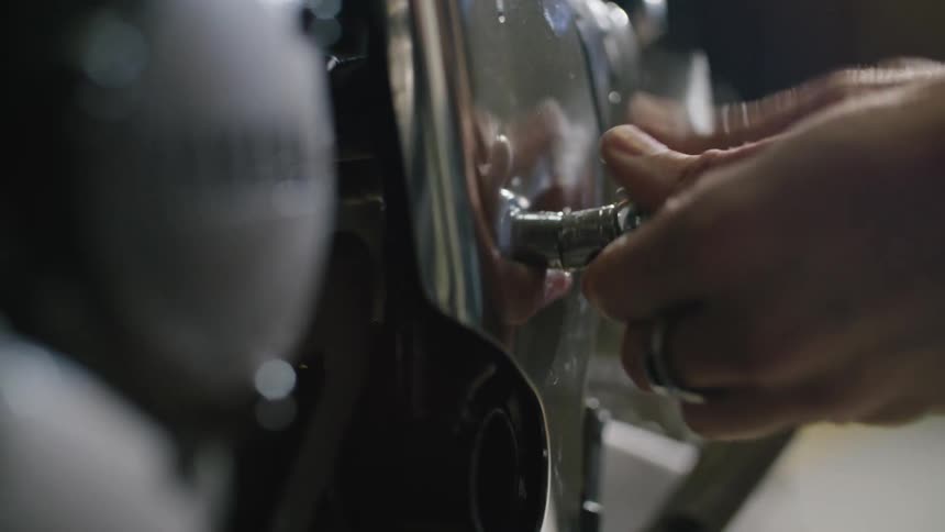 A person uses a torque tool to loosen a bolt and unfasten a metal panel