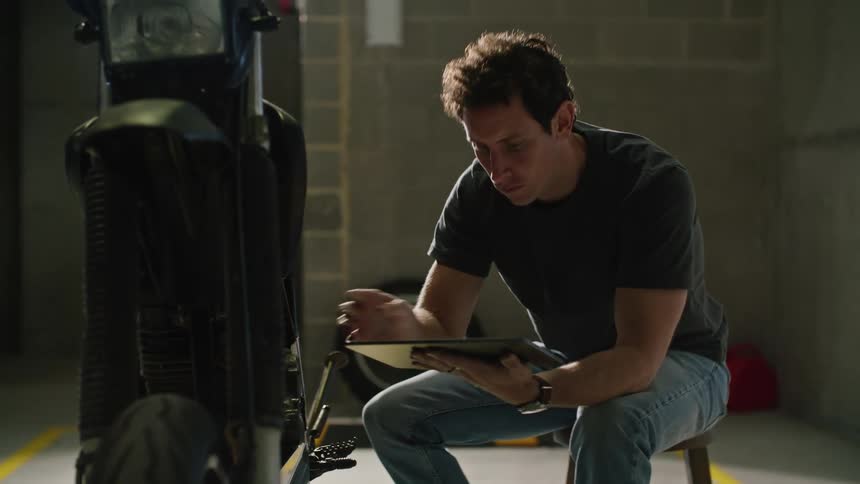 A man is checking his motorcycle with a tablet