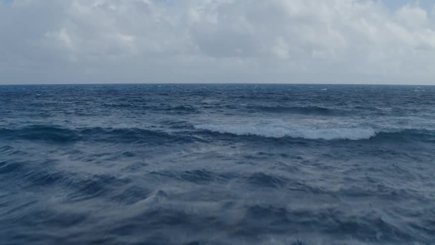 Skimming over breaking waves with a fast rise to reveal vast blue ocean