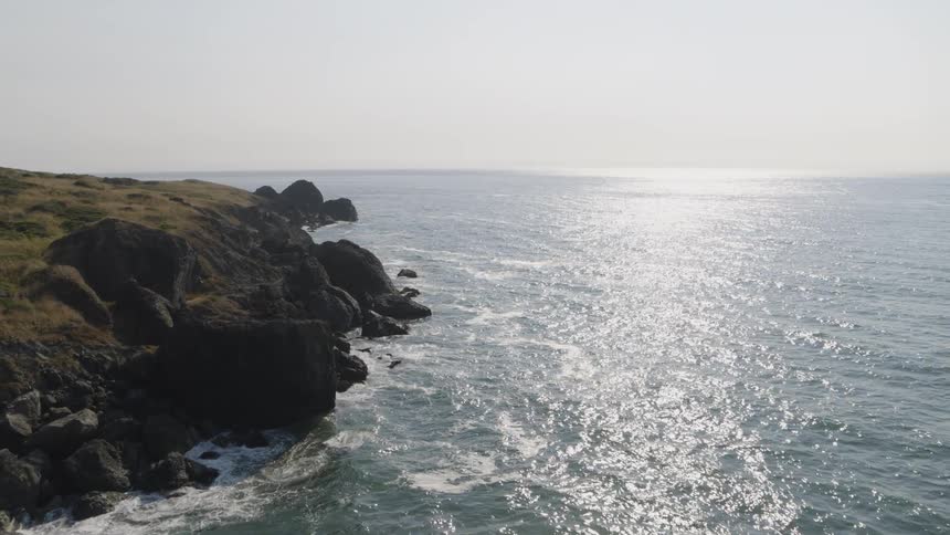 Rolling waves from open ocean break along a beautiful and remote rugged coastline