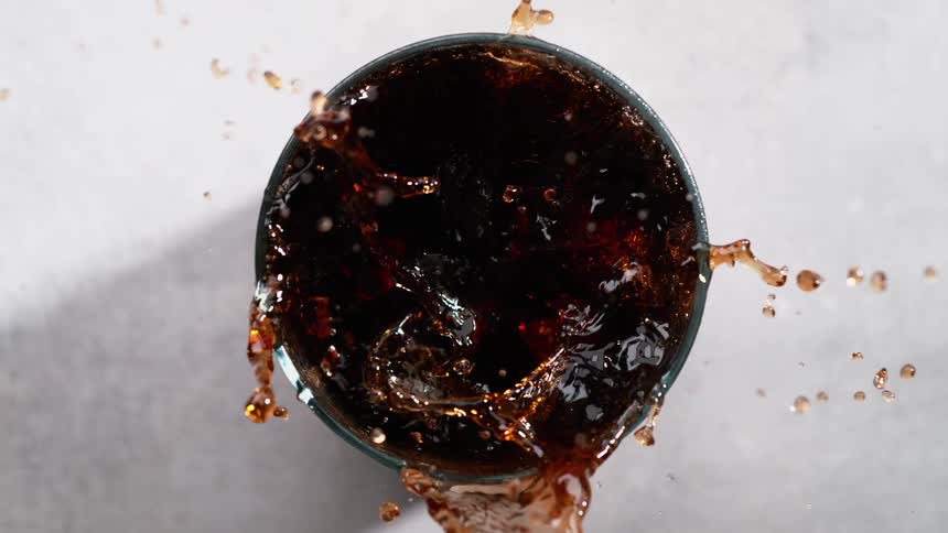 Slow motion view of ice cubes being put into a beverage is displayed