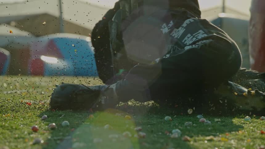 Man with black pants shoes and jacket slides across green lawn