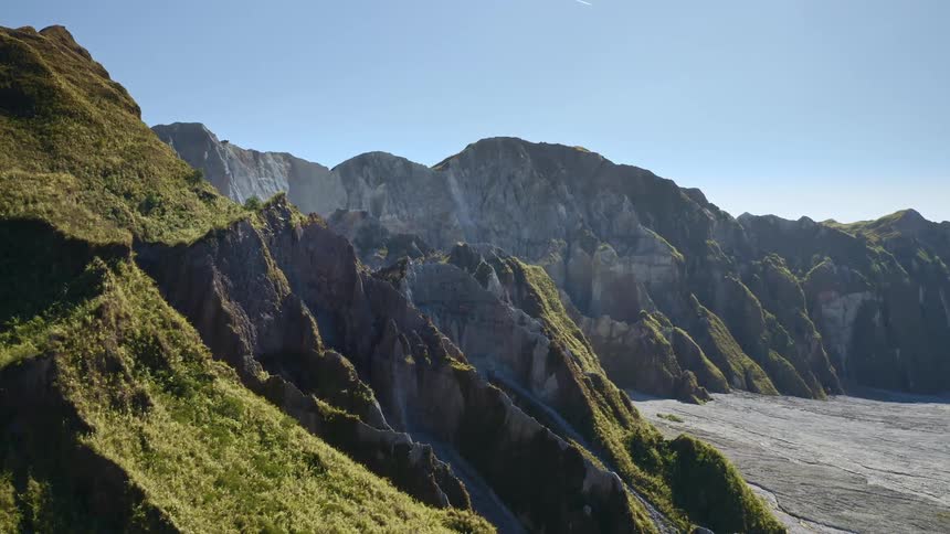 Aerial view of green mountain range along cliffs possibly coastal