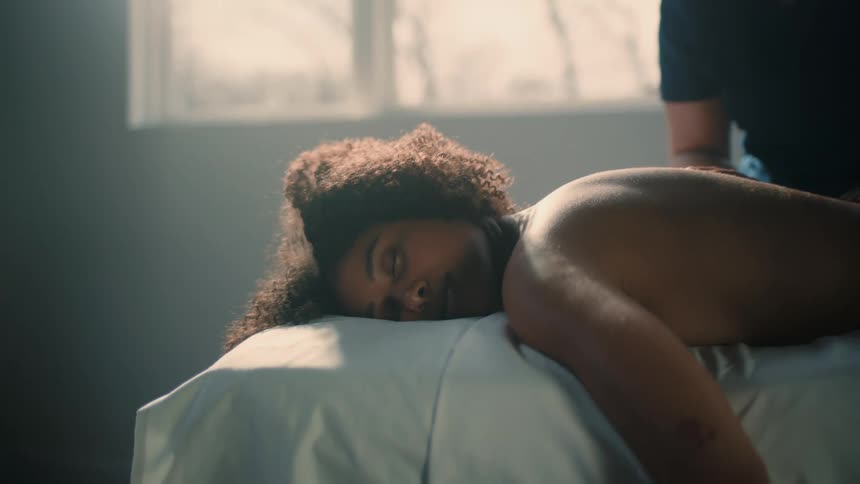 A content woman lays facedown as hands massage her back