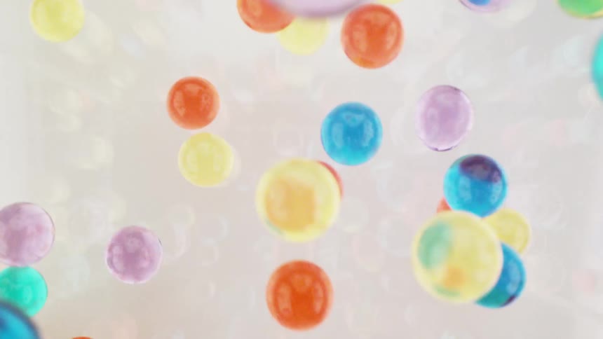 Colorful balls bounce around after falling into a white liquid
