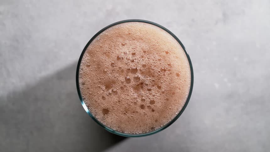 An up close view of a fizzy drink in a glass casting a shadow on the counter