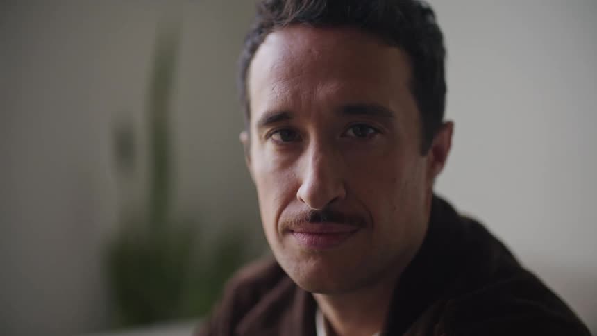 A man is sitting in a room looking ahead