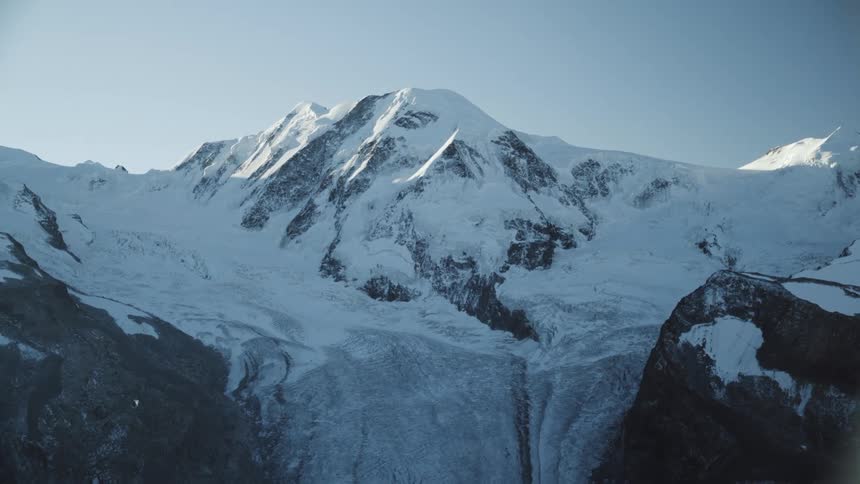 A static image of a snowcovered mountain crag peak in broad daylight
