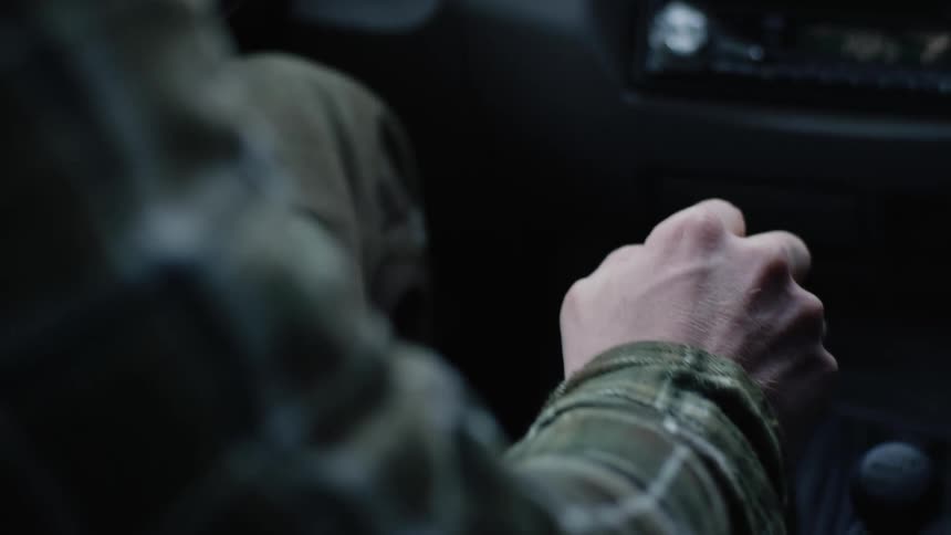The driver of an automobile takes their hand off the steering wheel to move the gear shift
