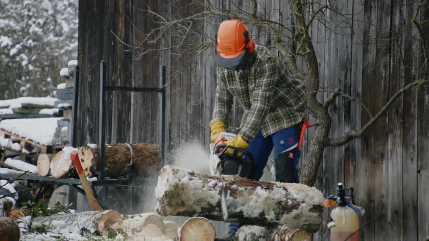 A man is cutting wood outdoors with a saw