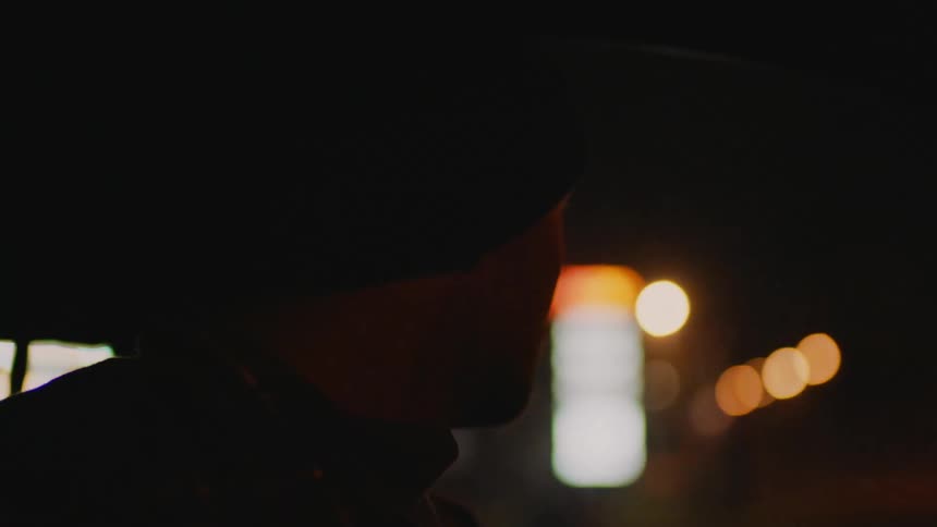 A man is looking around as he drives an automobile through town at night
