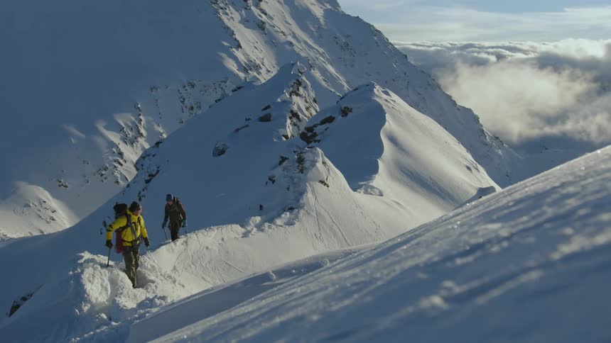 Two people are rock climbing up a mountain during winter