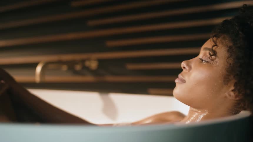 An up close of a woman in a bathtub rubbing soapy water over her legs
