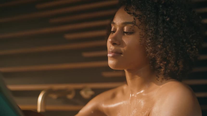 Woman with curly hair having a bath reads a book
