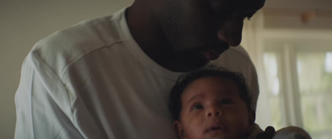 A father holds his infant son bouncing up and down as the infant looks off