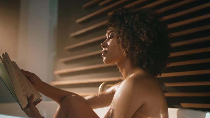 A woman sitting in her room lost in the pages of a novel the soft light illuminates the space around her as she delves deeper into the story