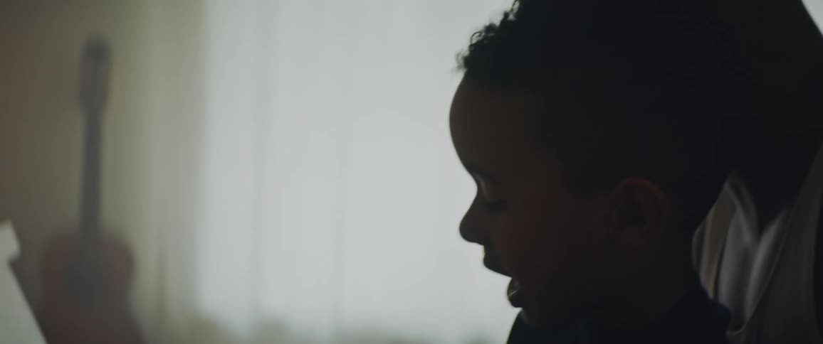Two silhouettes of a man and a child sitting together in front of a piece of furniture