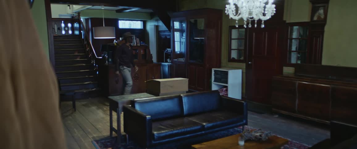 A large living room with a man walking down the stairs and out the door