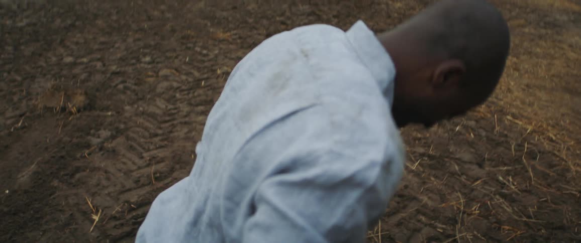 A man is carrying a piece of wood across the field