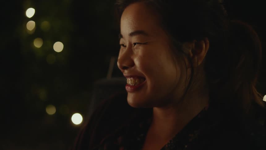 Close up of the face of a young woman talking to friends in a cozy room