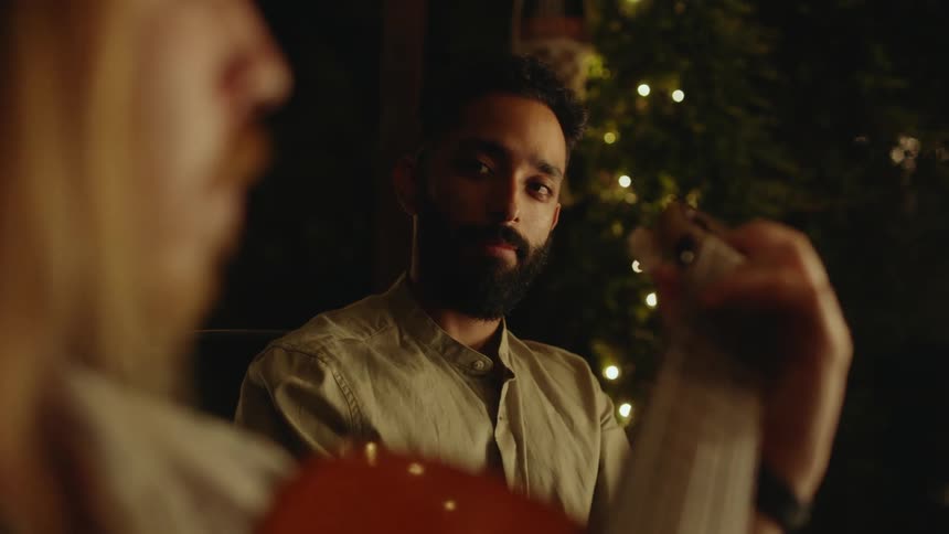 A man is listening to someone play guitar