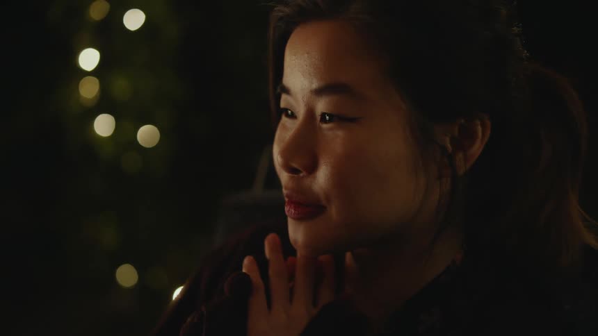 A woman is sitting down and talking during the night time
