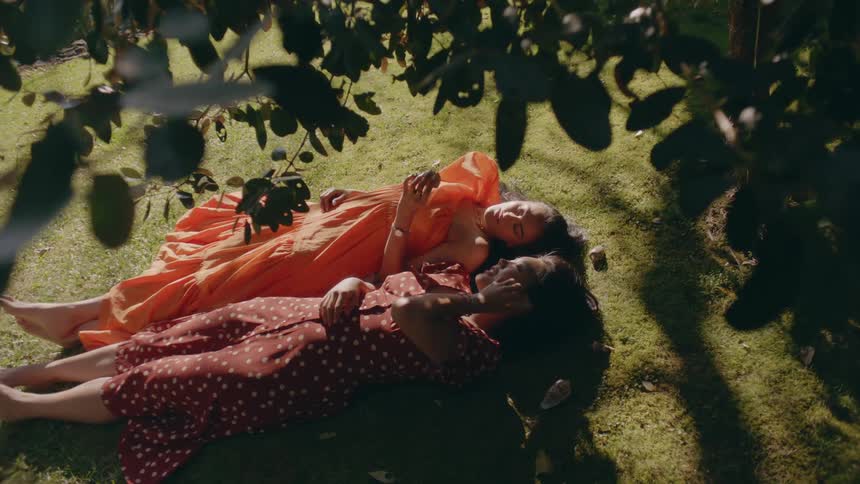 Two women are laying in a grassland area together