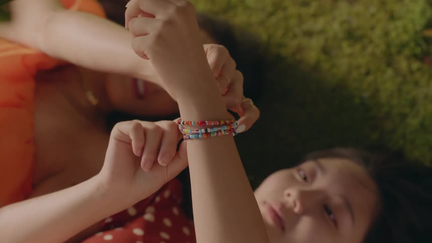 Two women examine bracelets while laying down