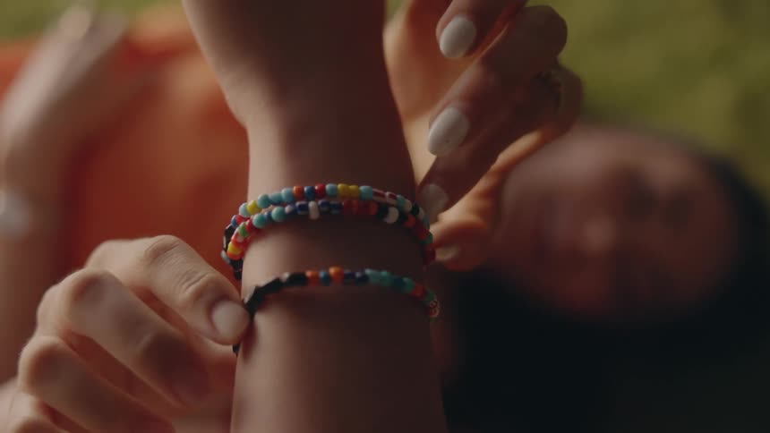 A girl turns beaded bracelets on another persons arm