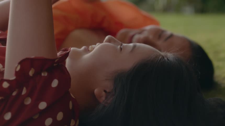 Two friends are laughing and laying in the grass together