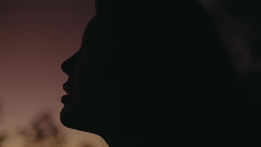 Side profile of woman is being silhouetted against the sky at dusk