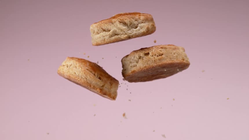 Close up of three biscuits jumping in the air against a pink background