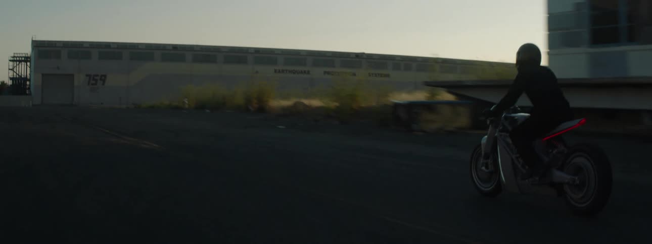 Motorcycle passes by old building at sunset