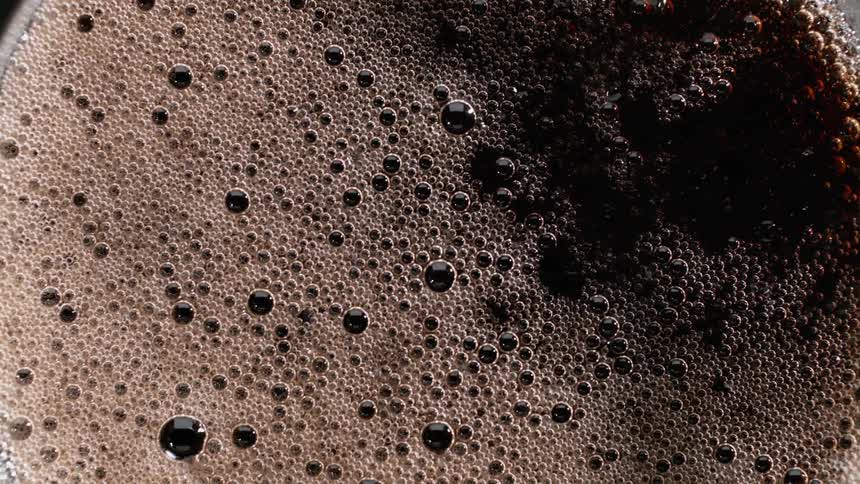 Bubble in foam on cola beverage slowly pop and fade