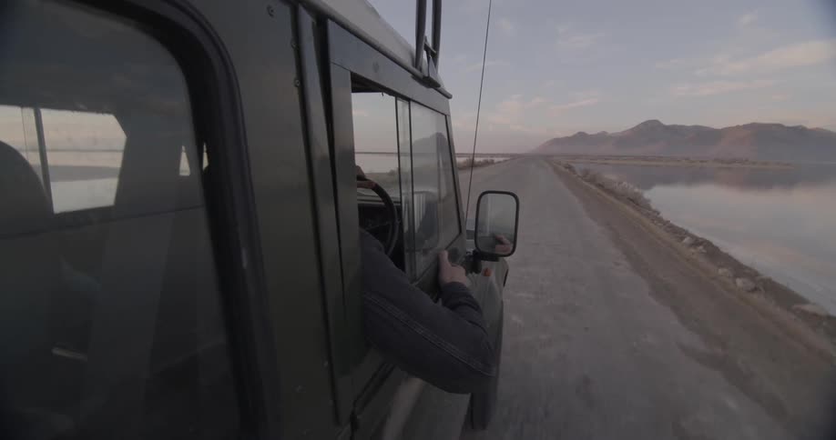 A vehicle is riding down a small trail through a lake