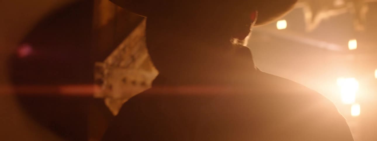 Silhouette of a cowboy opening the door of a shack against the bright lights from the inside