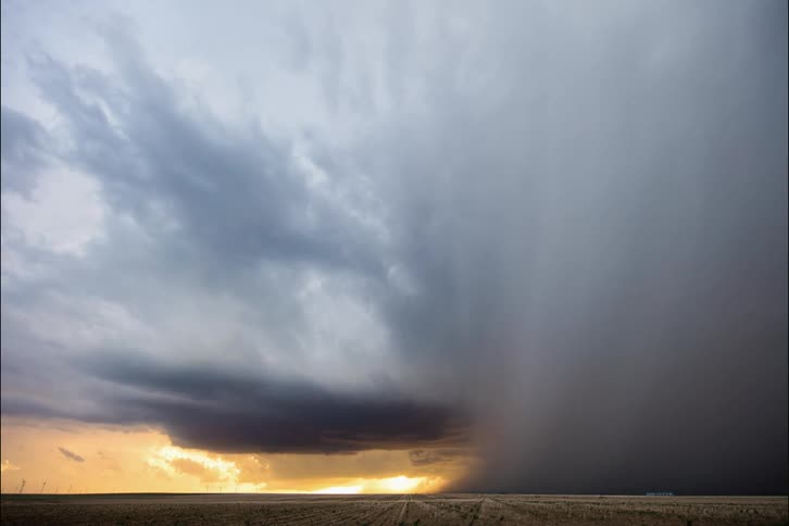 A tornado cloud moves over a field