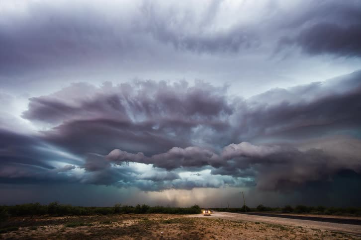 A landscape view of dark clouds rolling in and lighting flashing