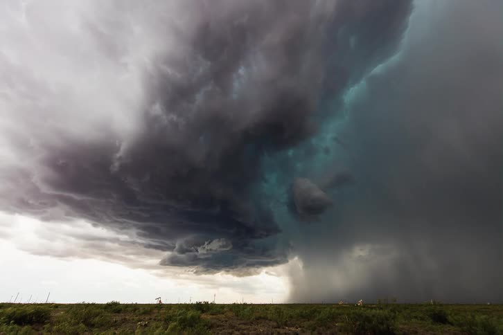 Dark storm clouds gather in the sky over green field