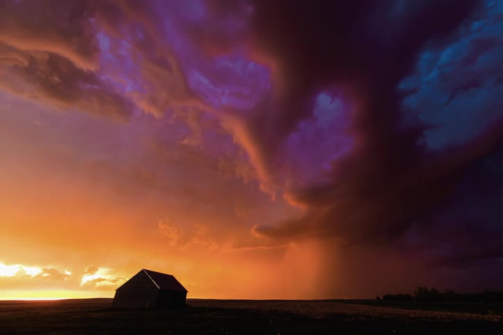 A storm is brewing during sunset in a rural area