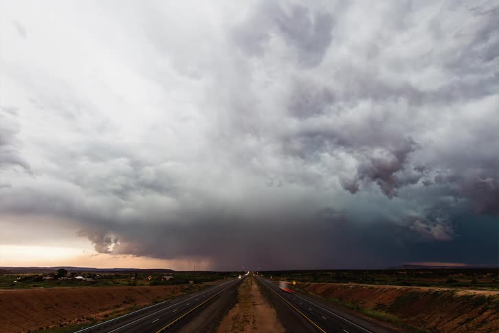 Traffic flows along highway as tons of lighting flashes in the distance