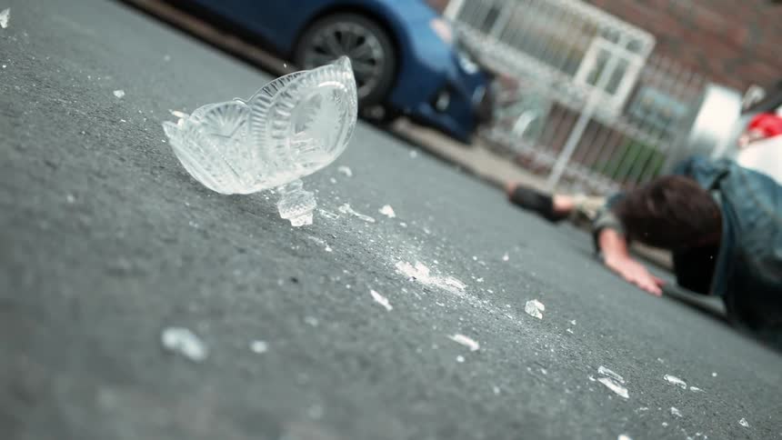 A man avoids a glass vase that fell from the sky in city street