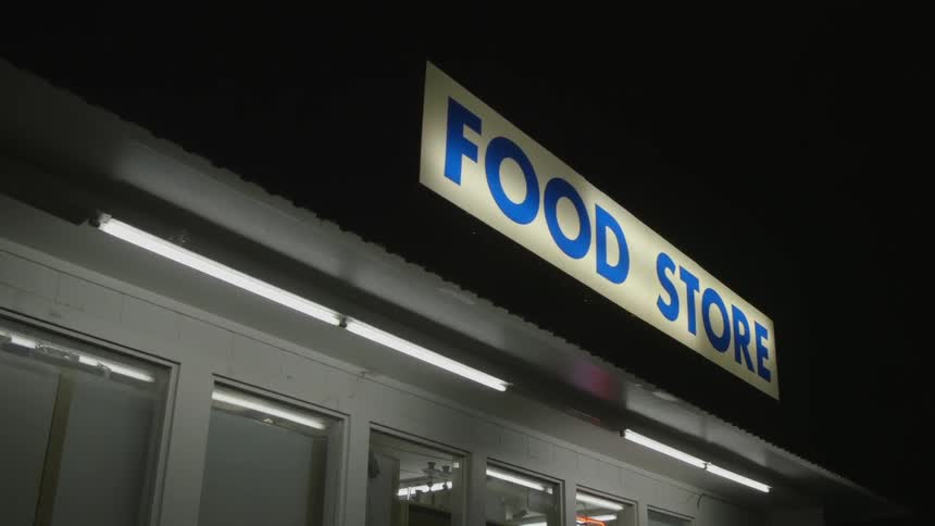 A store has a lit sign at night