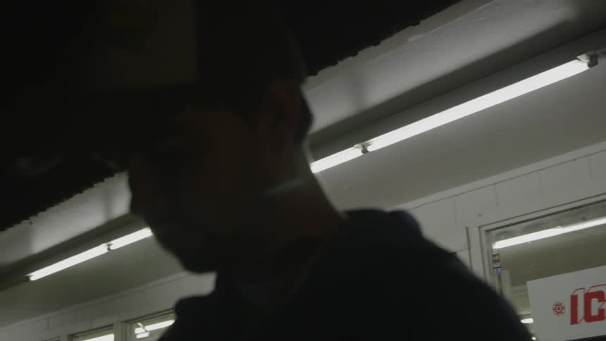 A man stands in the dark in front of a shop