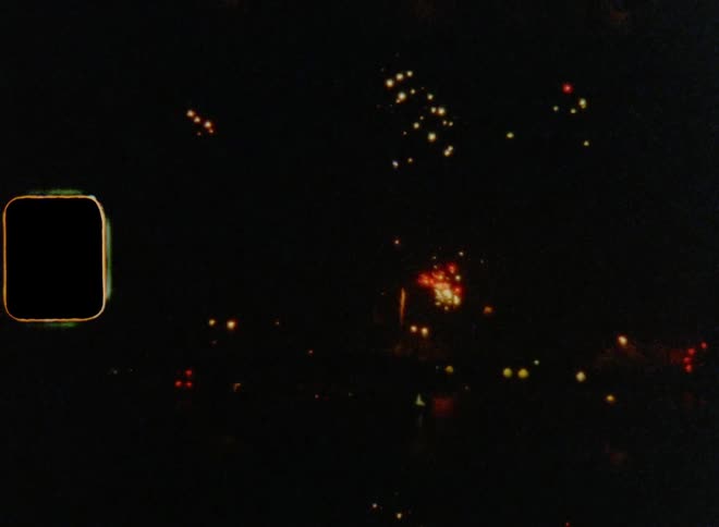 Water reflects fireworks display brightening up night sky over city celebrating a new beginning on old film footage