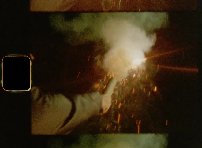 Man with cap and jacket raising his arm while holding a roman candle in his hand setting of fireworks during a protest at night