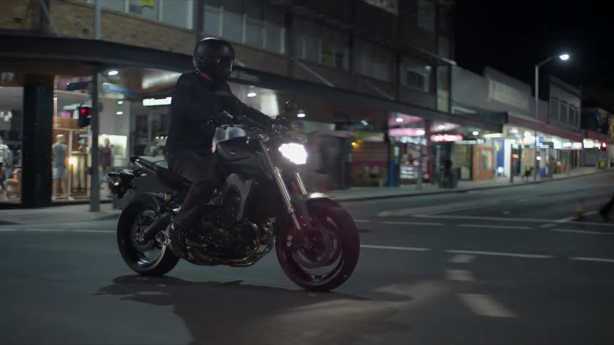 A man is driving a motorcycle through an urban city